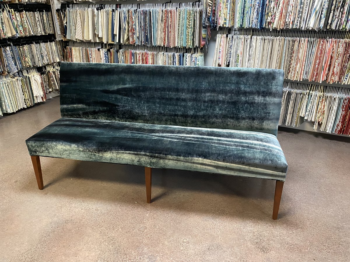 Custom teal velvet bench in front of the wall of fabric sample books at the Elvis Upholstery fabric store, Atlantic Beach FL